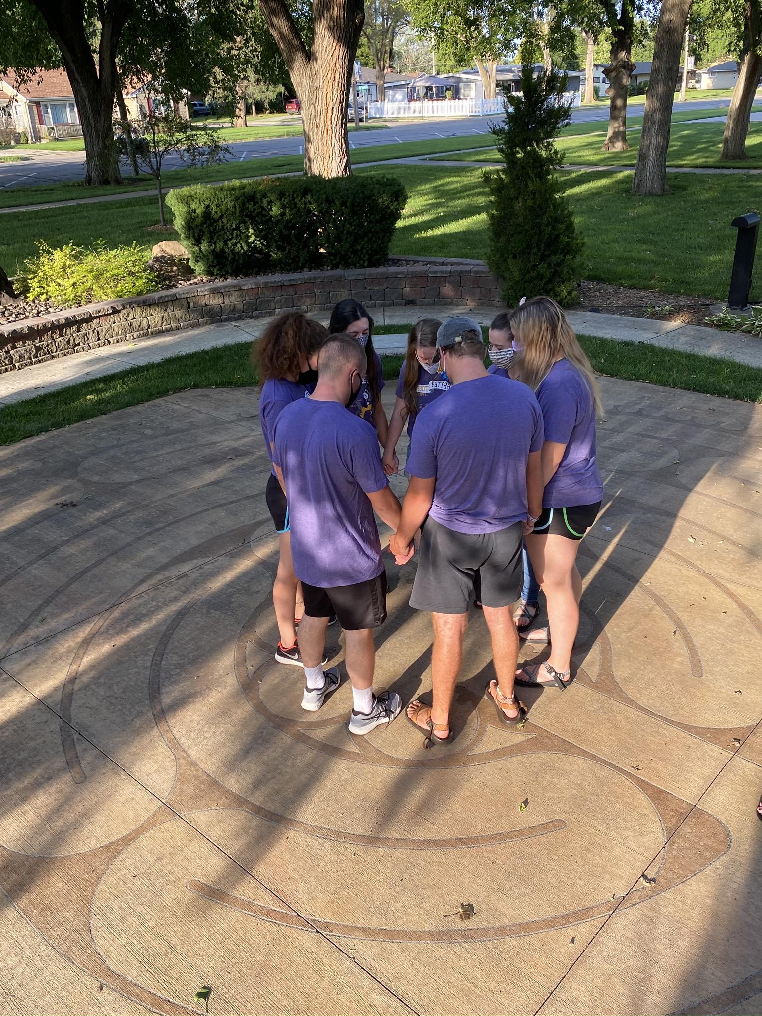 Group of people gathered around outside praying